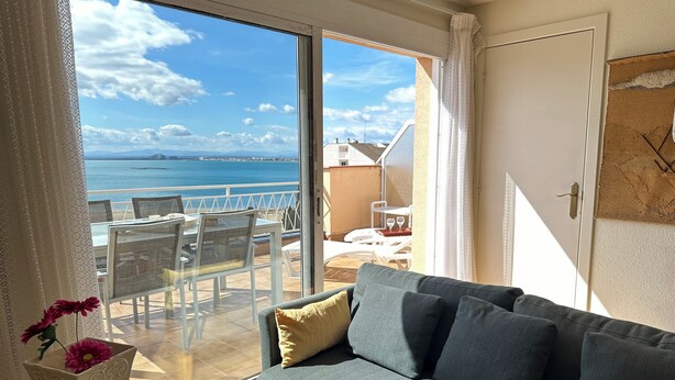 A balcony with a view of the sea, a sofa, and a table with a vase of flowers. - Agi Solimar C Atico B Apartamento for rent in Roses Girona. (Rosas / Roses)
