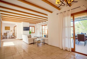 Relax in this spacious living area with a high ceiling, featuring a sofa set, glass coffee table, and television.