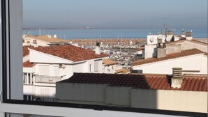 Un pueblo costero con tejados de tejas color terracota, un puerto deportivo y una vista despejada del mar.