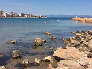 A coastal scene with clear waters, rocky shore, and a distant cityscape. - SPECTACULAR POOL-GARDEN, SEA VIEW, WiFi, PARKING, CABLE TV. HUT-027623  (L´escala)