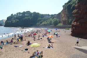 Een druk strand met mensen die zonnebaden en langs de kust wandelen.