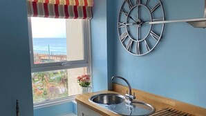 Una cocina con ventana, un reloj y vistas al mar.