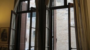A room with a large window, a chair, and a small table. - A magnificent XVth Century gothic Noble Palace on two canals. (Venezia)