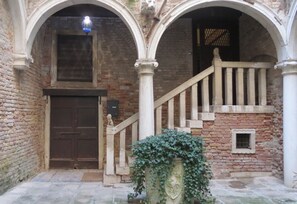 Un bâtiment historique doté d’une porte en bois, d’un escalier en pierre et d’une urne décorative.