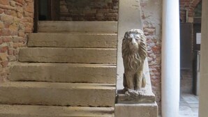 A stone staircase with a lion statue at the top, leading to a brick wall. - A magnificent XVth Century gothic Noble Palace on two canals. (Venezia)
