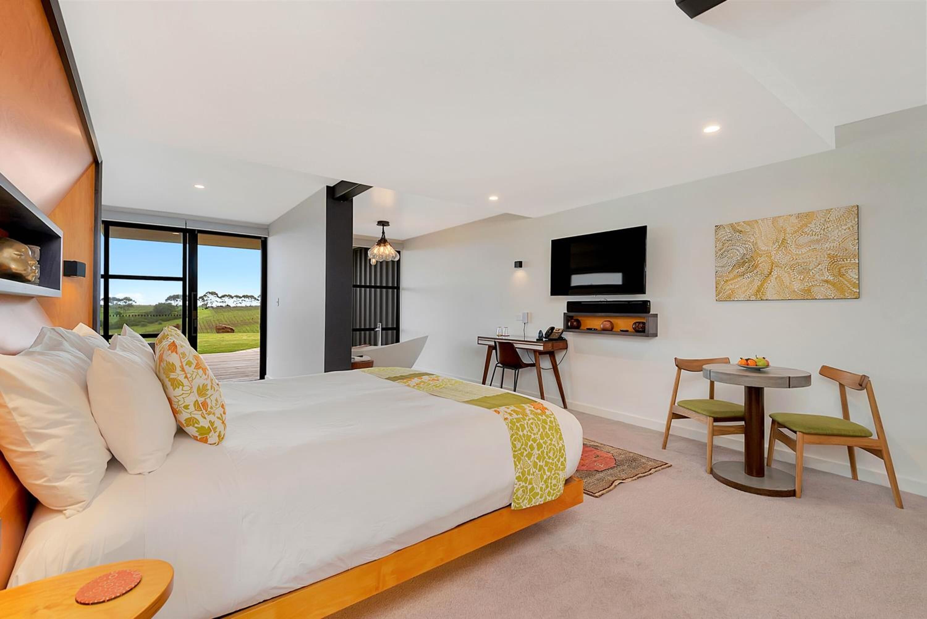 A modern bedroom with a large bed, a desk, and a dining area.