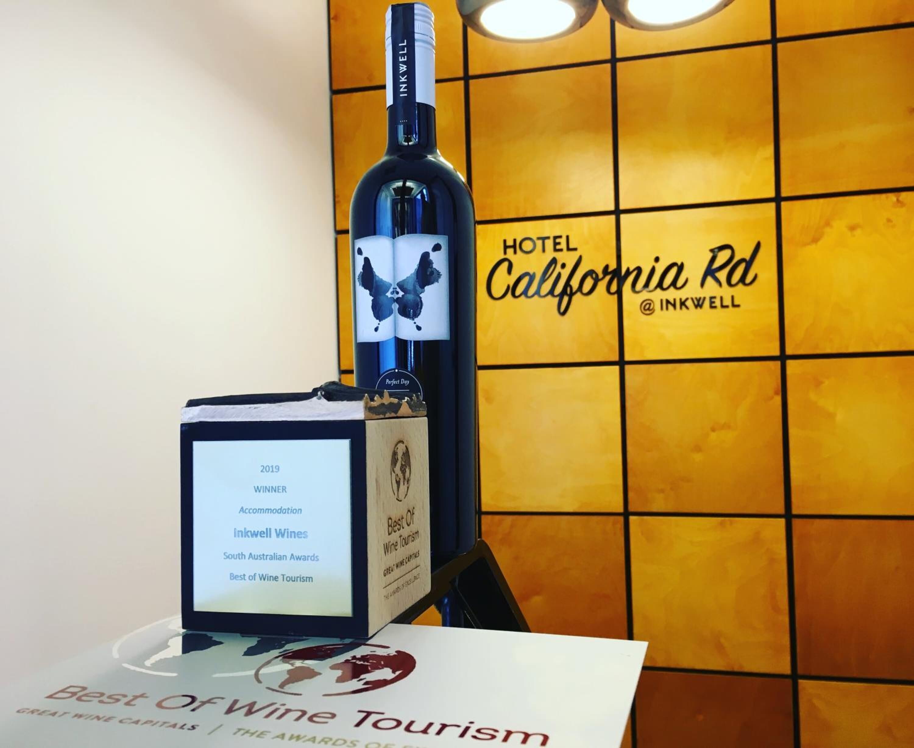 A bottle of wine on a display stand with a sign indicating it won an award in 2019 for Accommodation, Inkwell Wines, South Australian Awards, and Best of Wine Tourism.