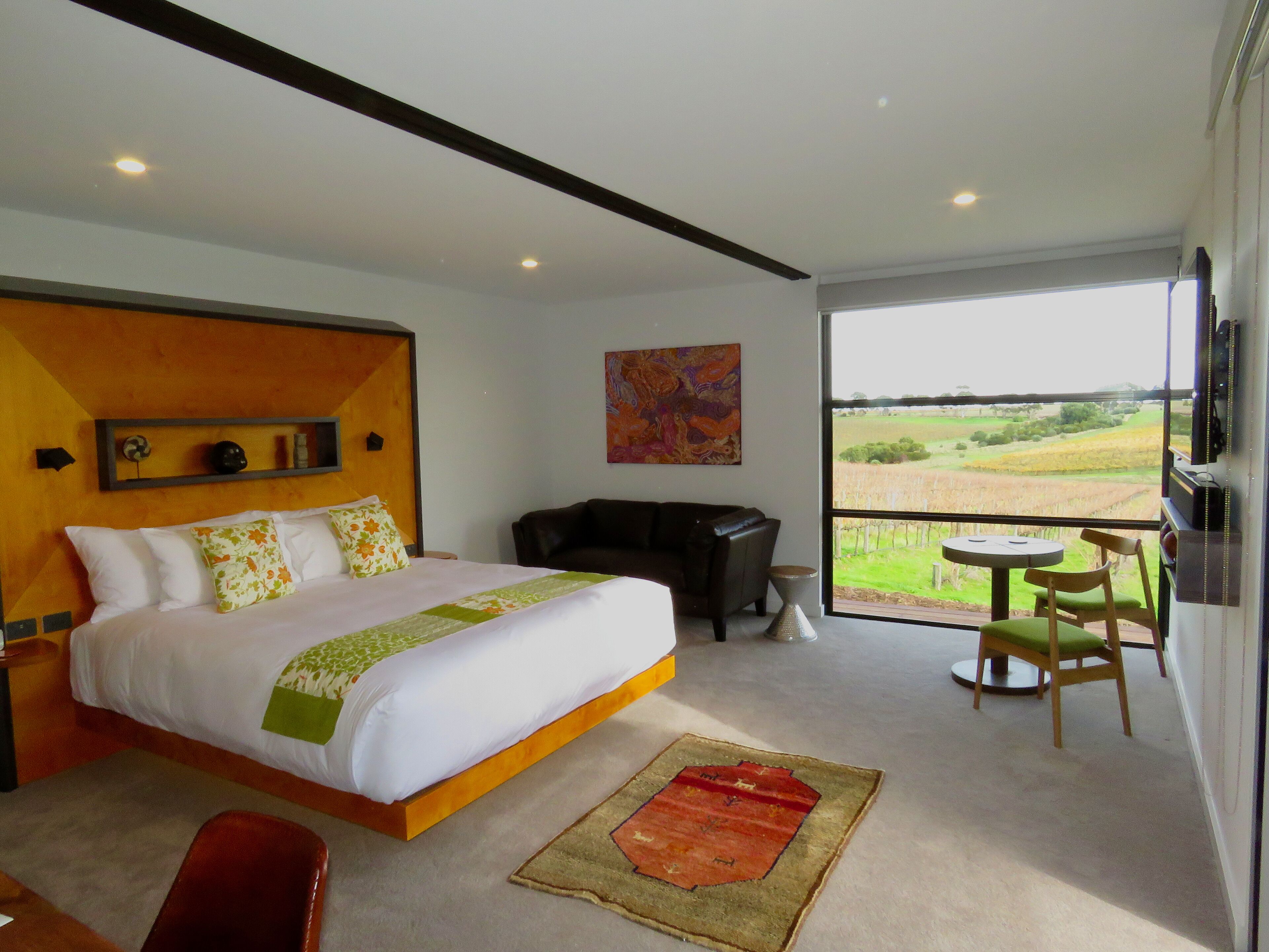A modern hotel room with a large bed, a desk, a chair, and a view of the countryside.