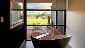 A modern interior with a large window, a dining area with a table and chairs, and a unique light fixture. - Hotel California Road at Inkwell Wines (Tatachilla)