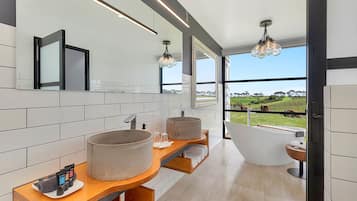 A modern bathroom with two large sinks, a freestanding bathtub, and a large mirror.