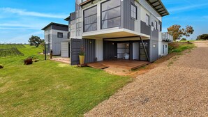 A modern two-story house with a large deck, surrounded by a well-maintained lawn and a gravel driveway. - Hotel California Road at Inkwell Wines (Tatachilla)
