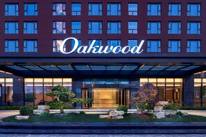 A hotel entrance with a large sign reading "Oakwood." - Oakwood Apartments Yangzhou (Yangzhou)