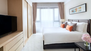 Habitación de hotel moderna con una cama grande, un televisor de pantalla plana y vistas a la ciudad a través de grandes ventanales.