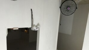 A room with a large window, a wall-mounted fan, and a partial view of a door.