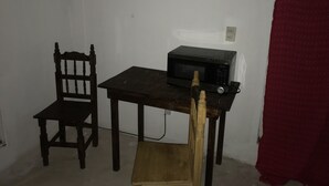 A small room with a wooden chair, a table, and a microwave.