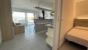 Une cuisine moderne dotée d’un îlot central intégré, d’un coin repas offrant une vue agréable et d’un balcon aménagé avec du mobilier d’extérieur.