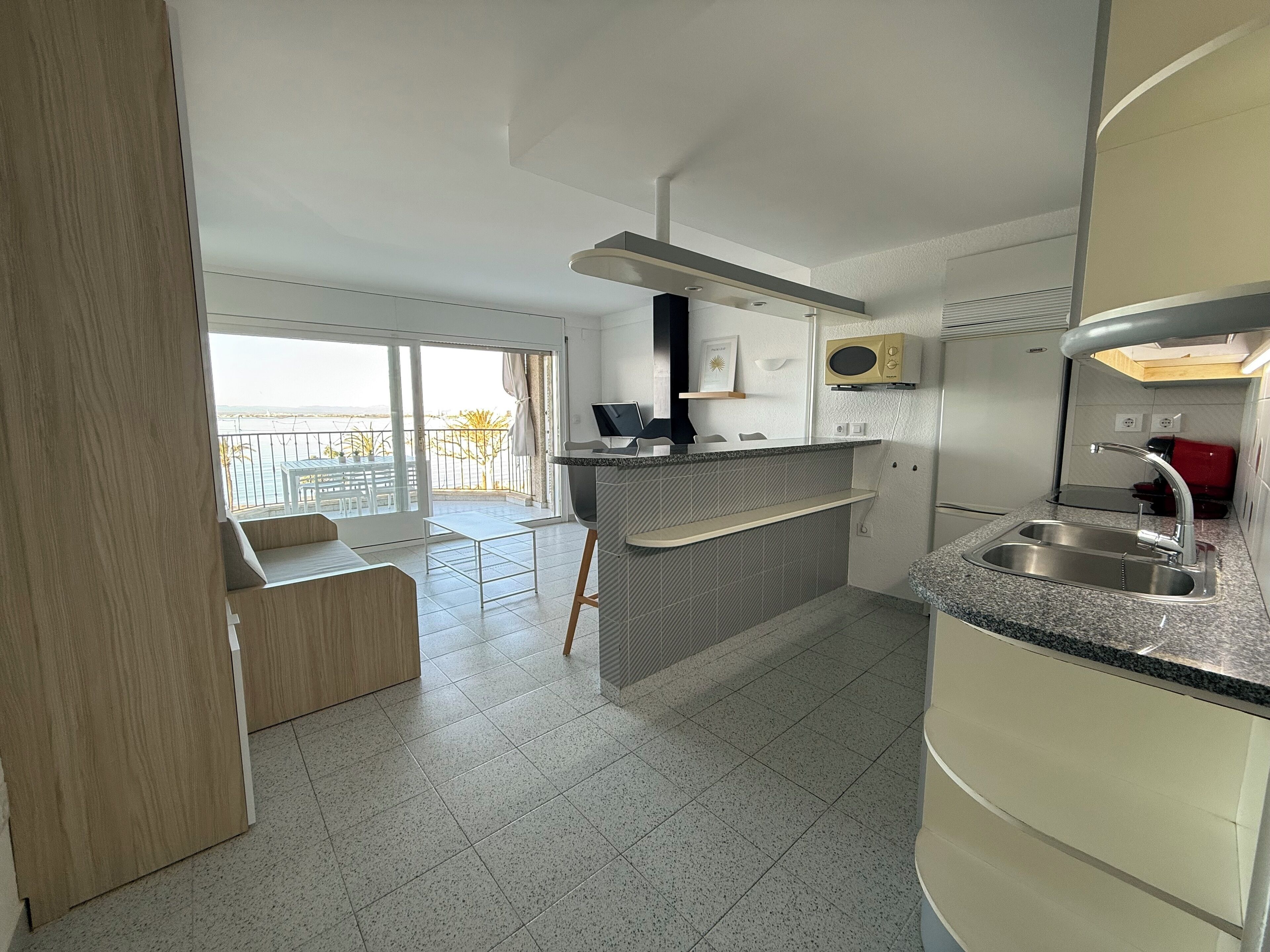A modern kitchen with a built-in microwave, a sink, and a dining area with a bench.