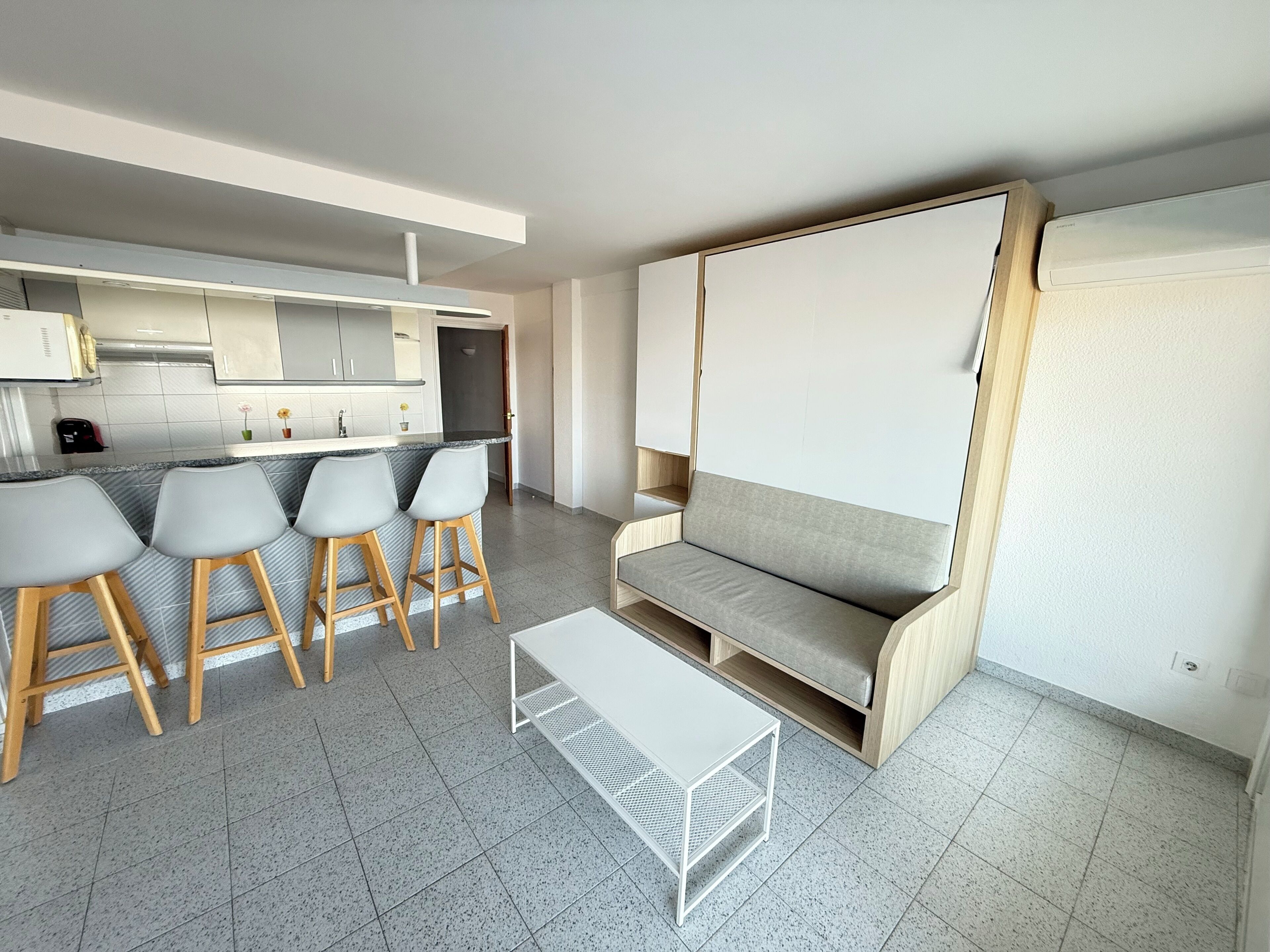 A modern kitchen with a bar area, a sofa, and a small table.