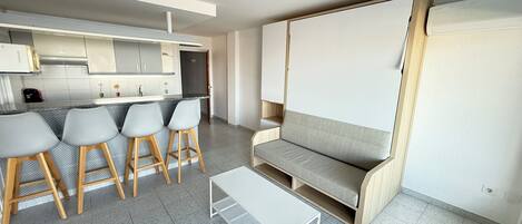 A modern kitchen with a bar area, a sofa, and a small table.