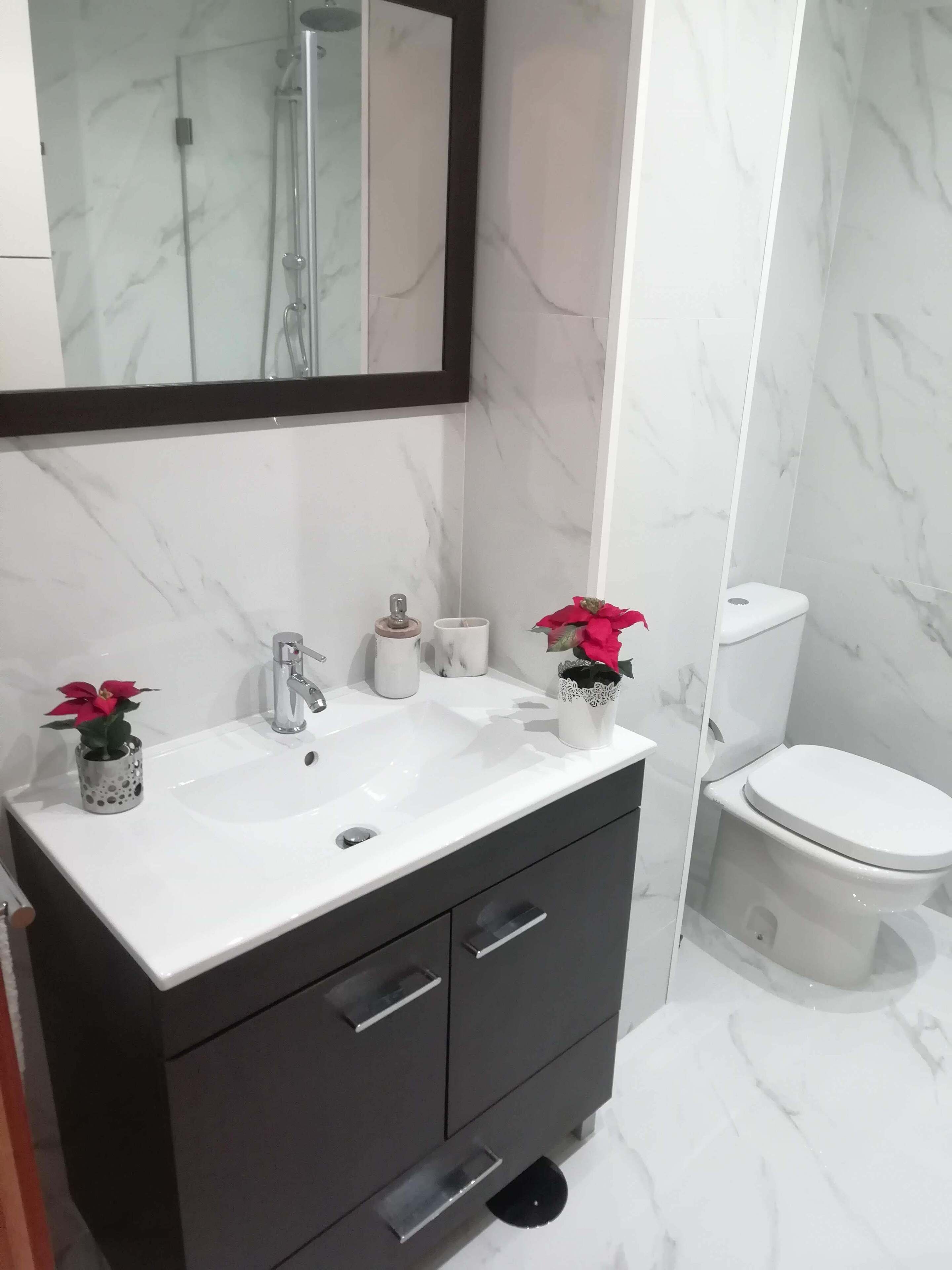 Ein Badezimmer mit Waschbecken, zwei Schubladen, einem Spiegel und einer Toilette.