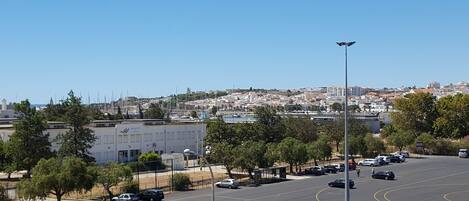 A parking lot with cars, a building with a sign, and a view of a town in the background.