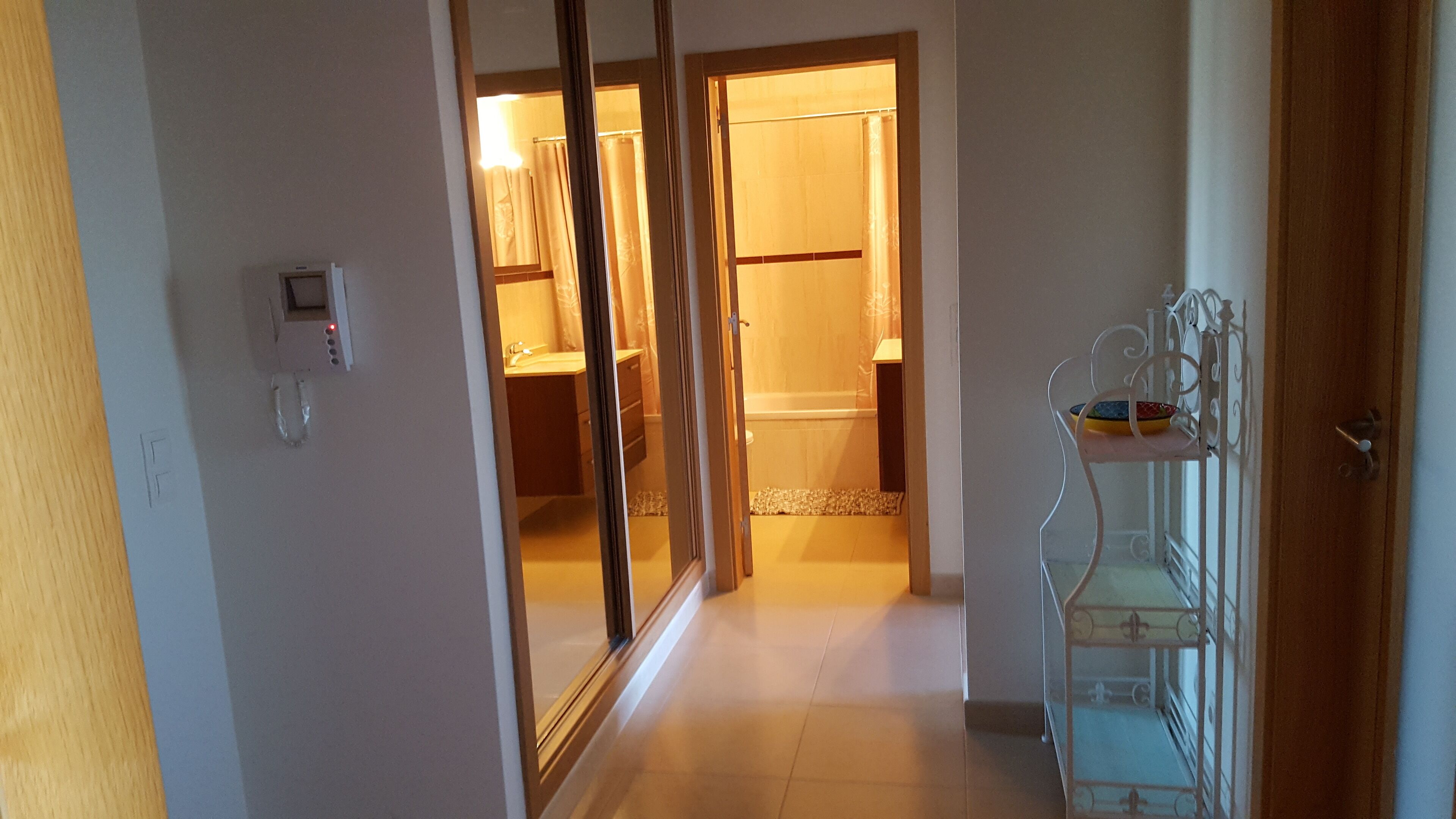 Un couloir menant à une salle de bain équipée de toilettes, d’un lavabo et d’une zone douche.