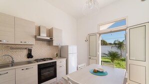 Une cuisine moderne avec un coin repas, un four encastré et une vue sur l’extérieur.