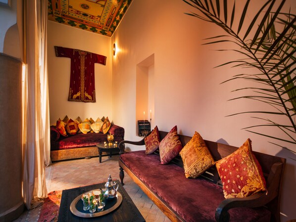 Una sala de estar acogedora con un sofá rojo y mullido, una mesita de centro con una bandeja de té y aperitivos, y un adorno decorativo en la pared.