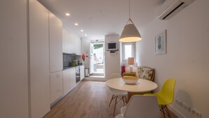 Una cucina moderna con mobili bianchi, una zona pranzo con un tavolo rotondo e sedie, e una lampada a sospensione luminosa.