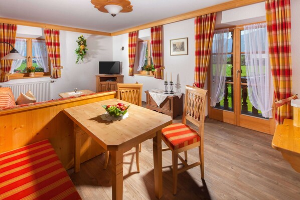 Une pièce chaleureuse avec une table à manger en bois, un banc et un téléviseur.