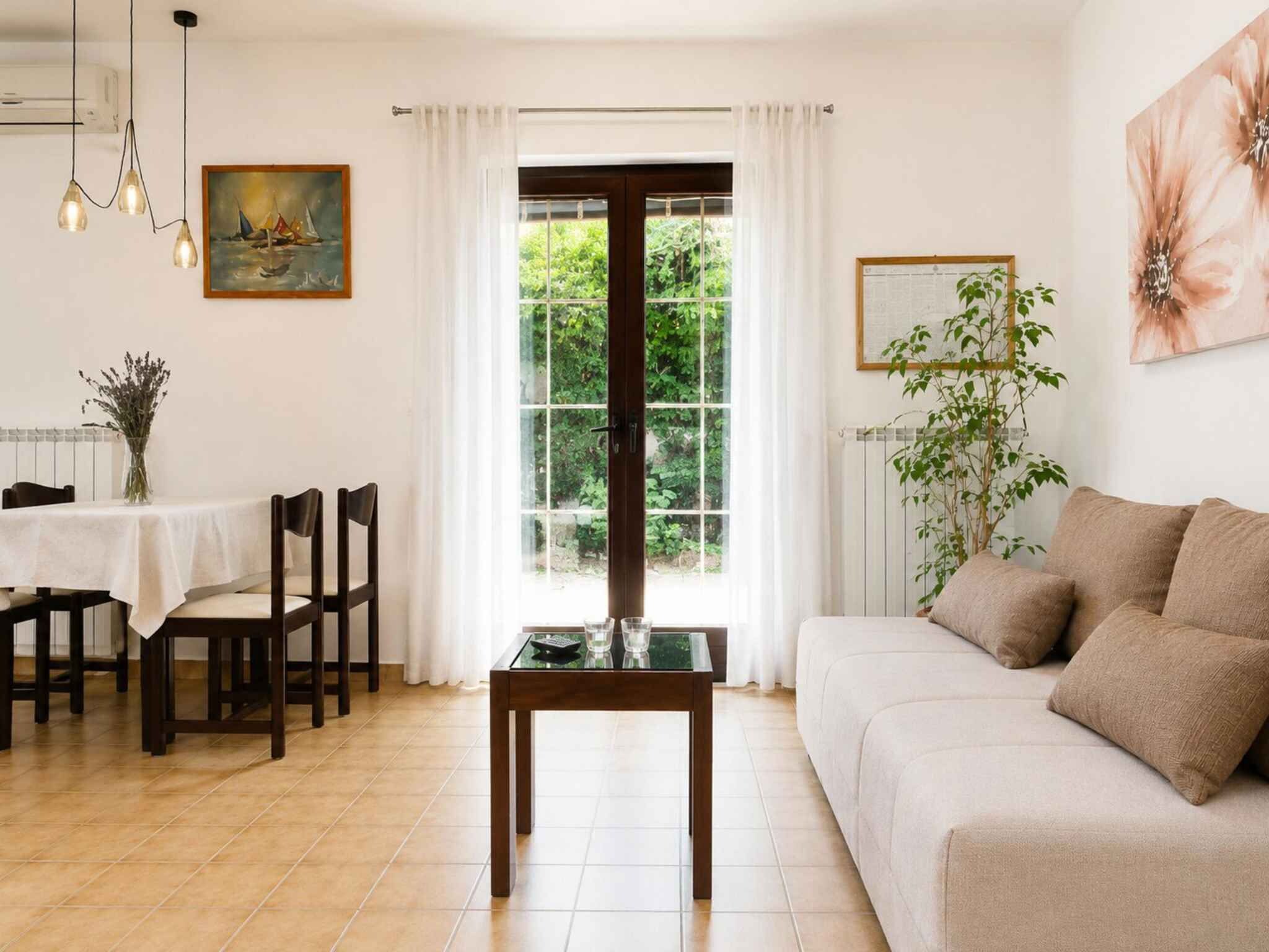 A well-lit living room with a sofa, dining table, chairs, and a glass coffee table.