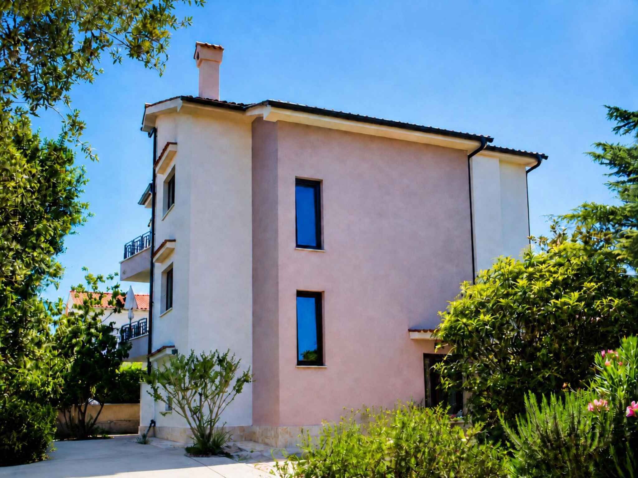 A two-story building with a flat roof, a chimney, and two visible windows.
