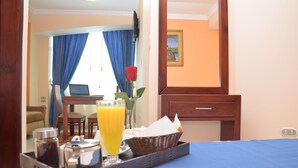 A hotel room with a bed, a tray with breakfast items, a laptop on a desk, and a view of the outdoors. - Hotel Perla Verde (Esmeraldas)
