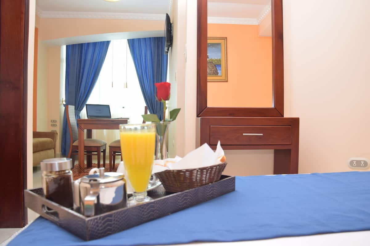Ein Hotelzimmer mit Bett, einem Frühstücksbrett und einem Laptop auf einem Schreibtisch, mit Blick ins Freie.