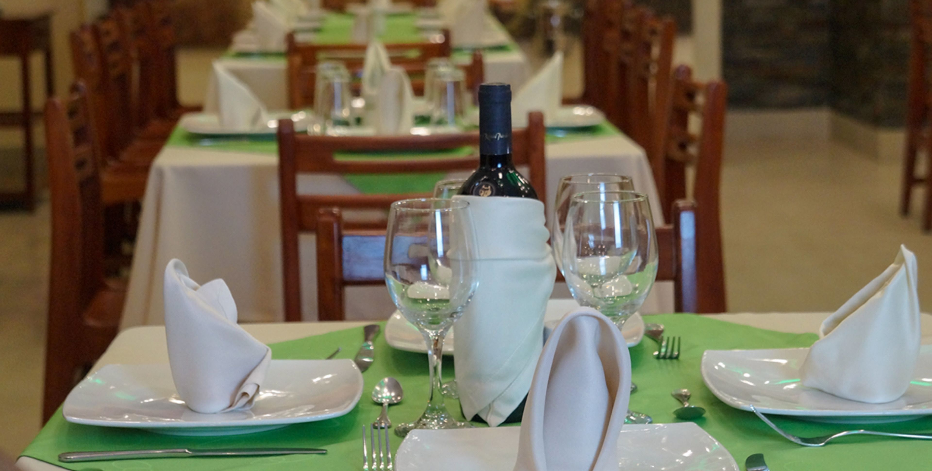 A dining table set with white plates, folded napkins, and wine glasses.