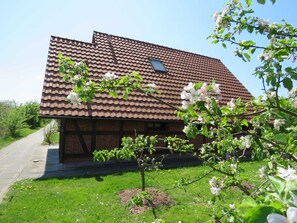 A two-story house with a brown tiled roof, a small window, and a brick facade.