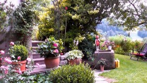 Un jardin avec des plantes en pot, une statue et une chaise.