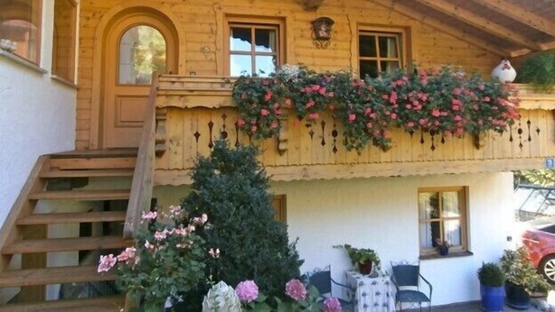 Un bâtiment en bois doté d’un balcon, d’un escalier et d’un petit sapin de Noël.