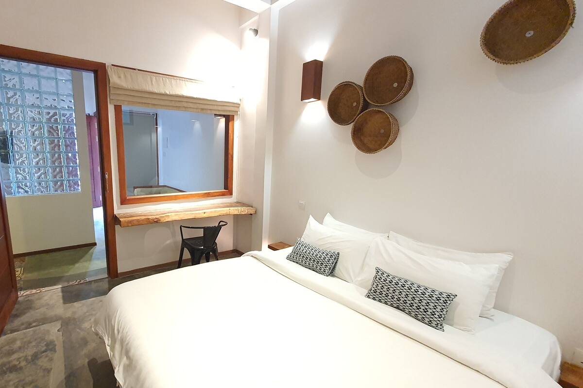 Ein Schlafzimmer mit Bett, Schreibtisch und Stuhl. Ein Fenster bietet Blick ins Freie.