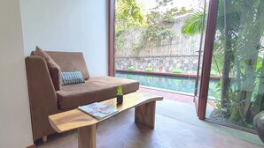 Una sala de estar moderna con un sofá marrón, una mesa de centro de madera y vistas a una piscina a través de amplios ventanales.