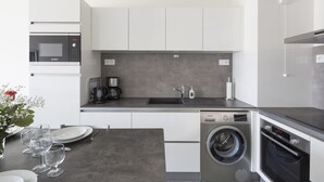 Eine kompakte Küche mit einer Bosch-Mikrowelle, einem Siemens-Geschirrspüler und einem Backofen, einem Spülbecken und einer Kaffeemaschine.
