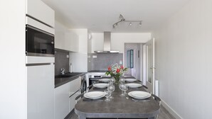 Eine moderne Küche mit Essbereich, ausgestattet mit Backofen, Mikrowelle und Edelstahlgeräten.