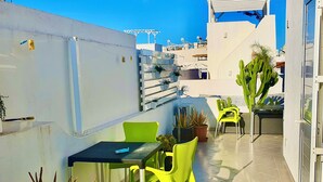 Une terrasse sur le toit, avec une table et des chaises, des plantes en pot et une vue sur le paysage urbain.