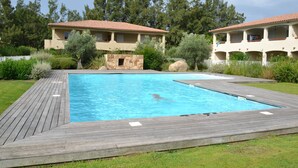 Ein rechteckiger Swimmingpool mit Holzboden, umgeben von einem gepflegten Rasen und Bäumen.