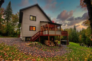 A two-story house with a covered porch and a staircase leading to the upper floor. - Le Bonheur-Spa / BIKE, OUTDOOR + SKI-IN / SKI-OUT (Morin-Heights)