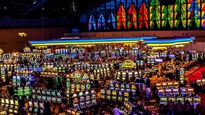 A casino with numerous slot machines and a vibrant stained glass window in the background.