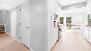A modern kitchen with white cabinets, a dining area with a table and chairs, and a view of the outdoors through a large window. - 3BR/2BA Spinnaker! Close to Beaches! Pet Friendly! Amenity access included! (Seabrook Island)