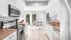 A modern kitchen with white cabinetry, stainless steel appliances, and a dining area with a table and chairs. - 3BR/2BA Spinnaker! Close to Beaches! Pet Friendly! Amenity access included! (Seabrook Island)