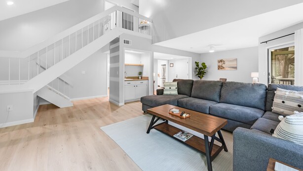 A spacious living area with a grey sofa, a wooden coffee table, and a staircase leading to an upper level. - 3BR/2BA Spinnaker! Close to Beaches! Pet Friendly! Amenity access included! (Seabrook Island)