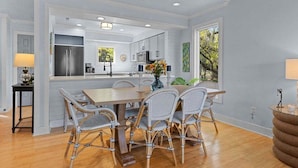 A modern kitchen with white cabinetry, a central island, and a dining area with wicker chairs. - Cozy 3BR / 3.5 BA Retreat - Neighborhood Pool!  access included! (Johns Island)